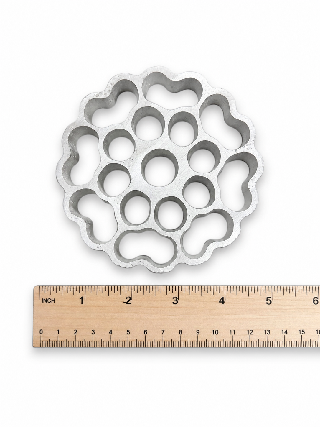 Flower-shaped metal buñuelo mold with ruler showing size